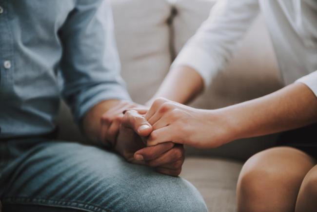 A close up of a man and woman holding hands tightly.