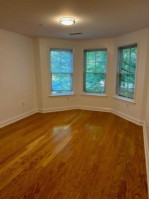 Second bedroom with hardwood flooring, bay windows, white walls, and overhead lighting