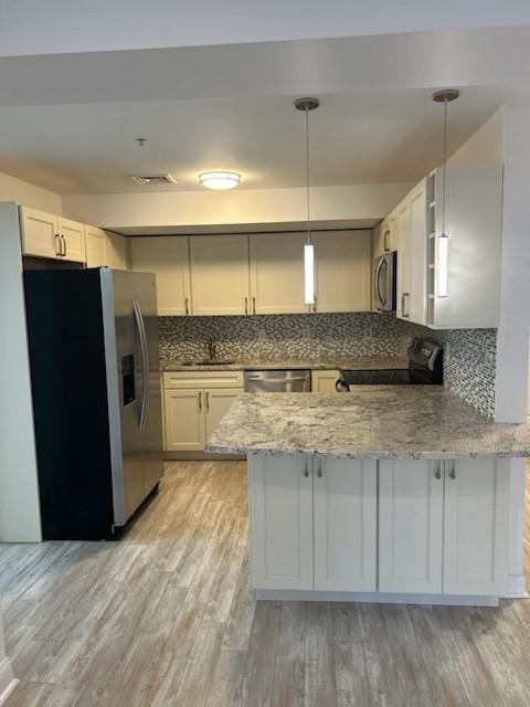 Kitchen with hard flooring, stainless steel appliances, granite countertop, and overhead lighting