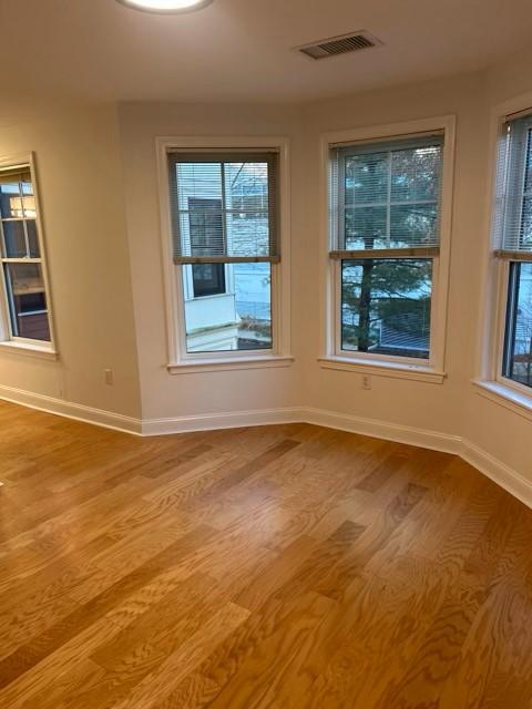 Spacious primary bedroom with hard flooring, overhead lighting, and large bay windows