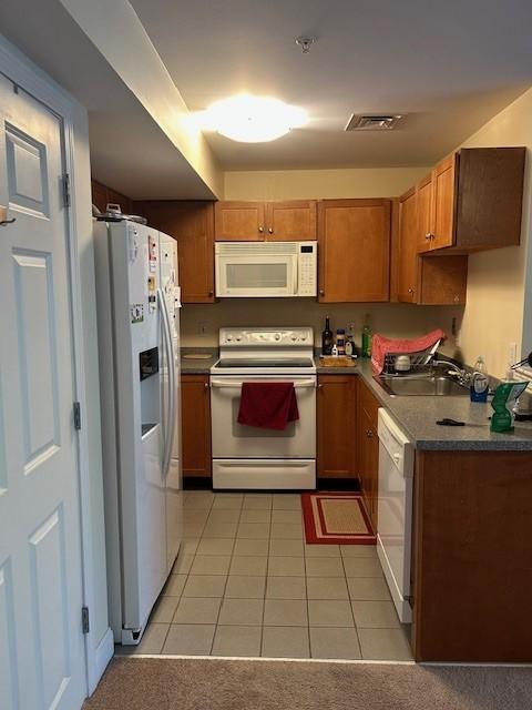 Kitchen with white appliances and tile flooring