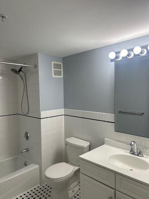 secondary bathroom with tub + shower, white tile flooring, toilet, and a vanity with sink and lower cabinetry