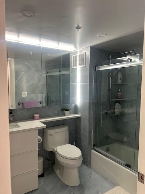 primary bathroom with glass shower door, shower/tub, toilet, mirror, and vanity