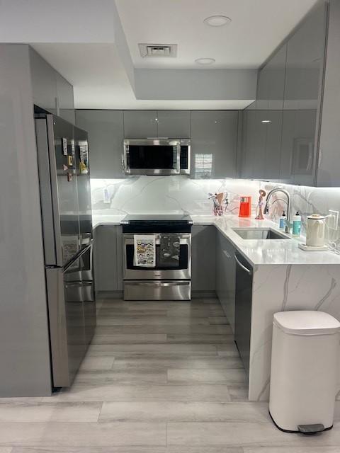 kitchen with stainless steel appliances, hard flooring, grey cabinetry and white countertops