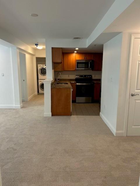 Open concept living and dining room with carpeted flooring, view of stacked washer and dryer appliances down the hall
