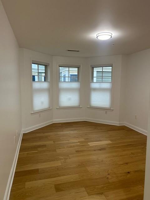 Primary bedroom with bay windows and hard flooring
