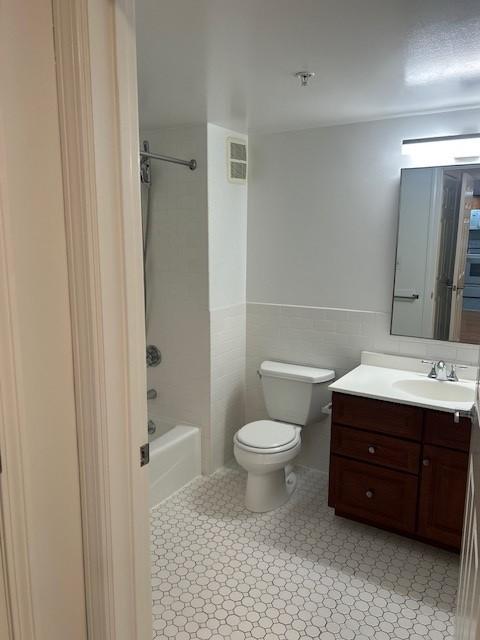 Primary bathroom with toilet, sink, vanity, and white tiling