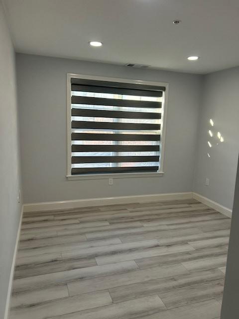 Second bedroom with large window and blinds, hard flooring, recessed lighting