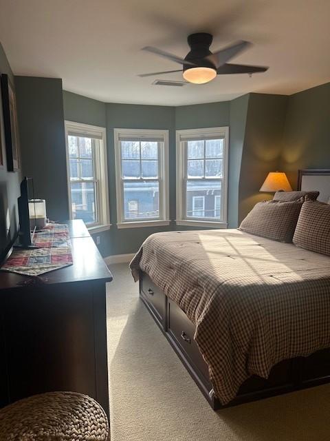 Primary bedroom with carpeted flooring, bay windows, and dark green walls